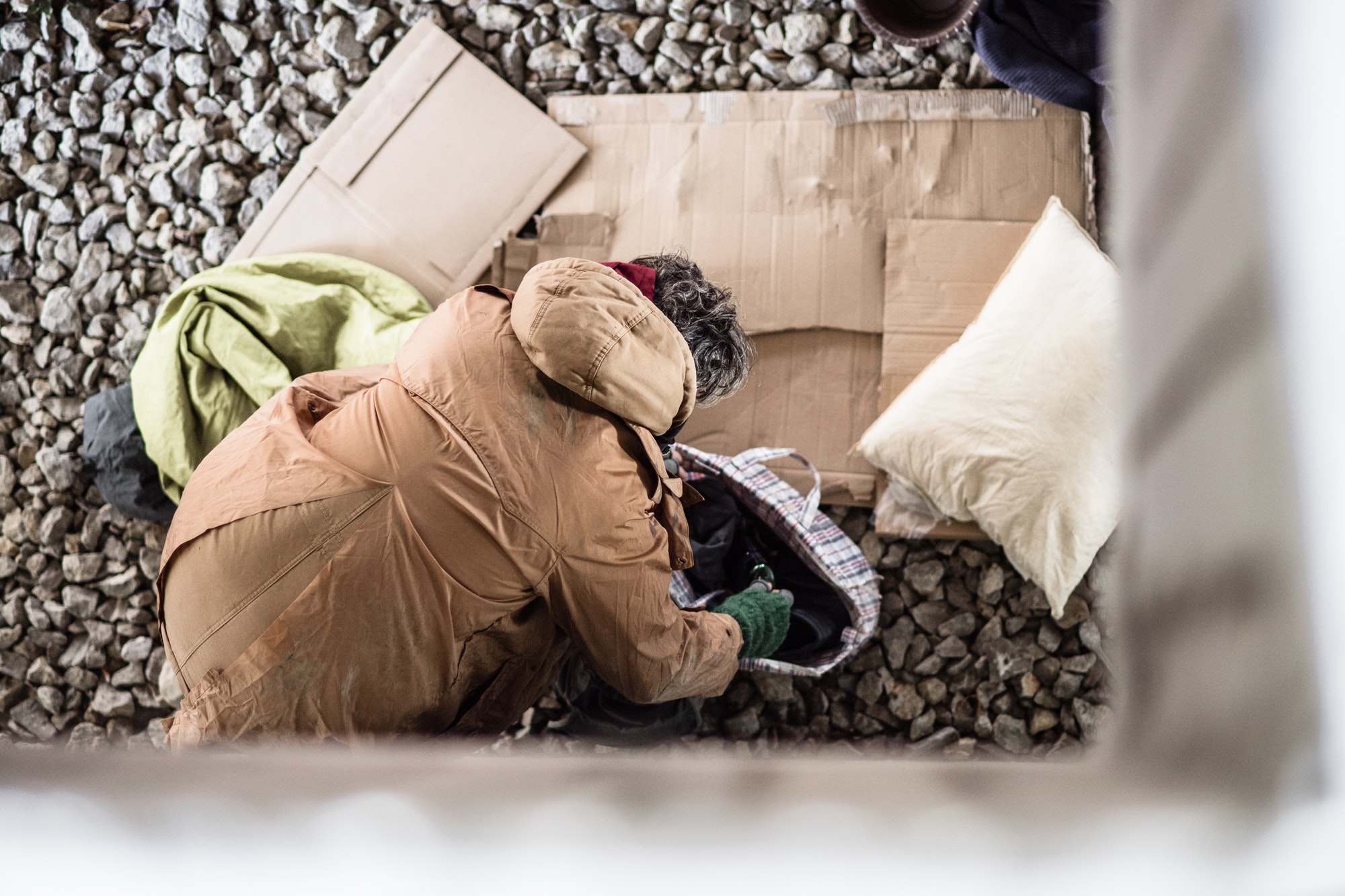 A top view of homeless beggar man with belongings outdoors in city.