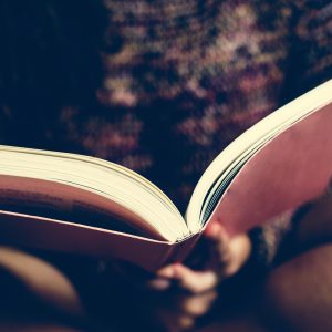 Teenage girl reading a book in a bedroom